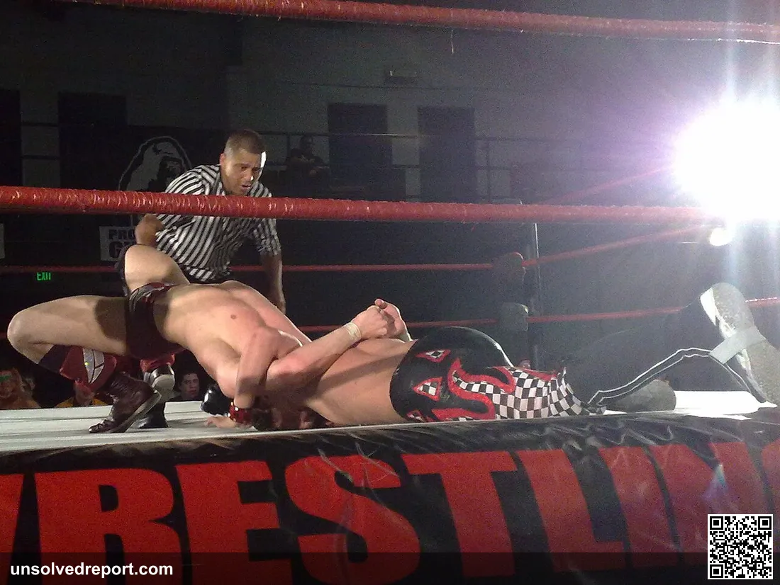 Bryan Danielson applying his Cattle Mutilation finishing hold (a bridging grounded double chickenwing) on TJ Perkins at…
